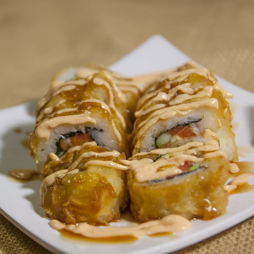 Veggie House's deep-fried vegetarian sushi rolls with creamy sauce and sweet glaze on a white plate.