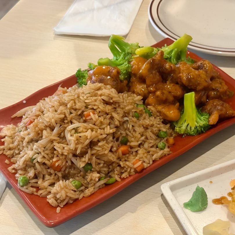 Veggie House's orange 'chicken' with broccoli and fried rice on a red rectangular plate.